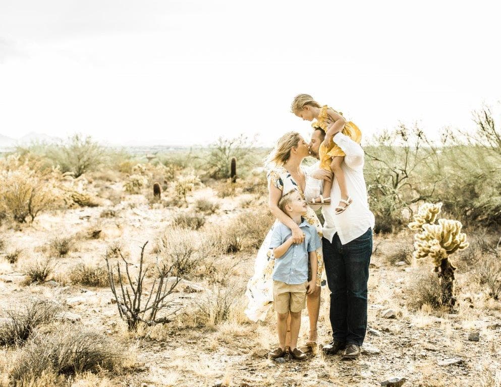 A family of four standing together in a bright Arizona desert landscape